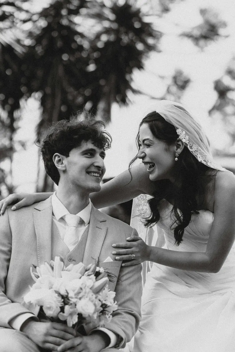 Bride and groom laughing together in a black and white wedding portrait